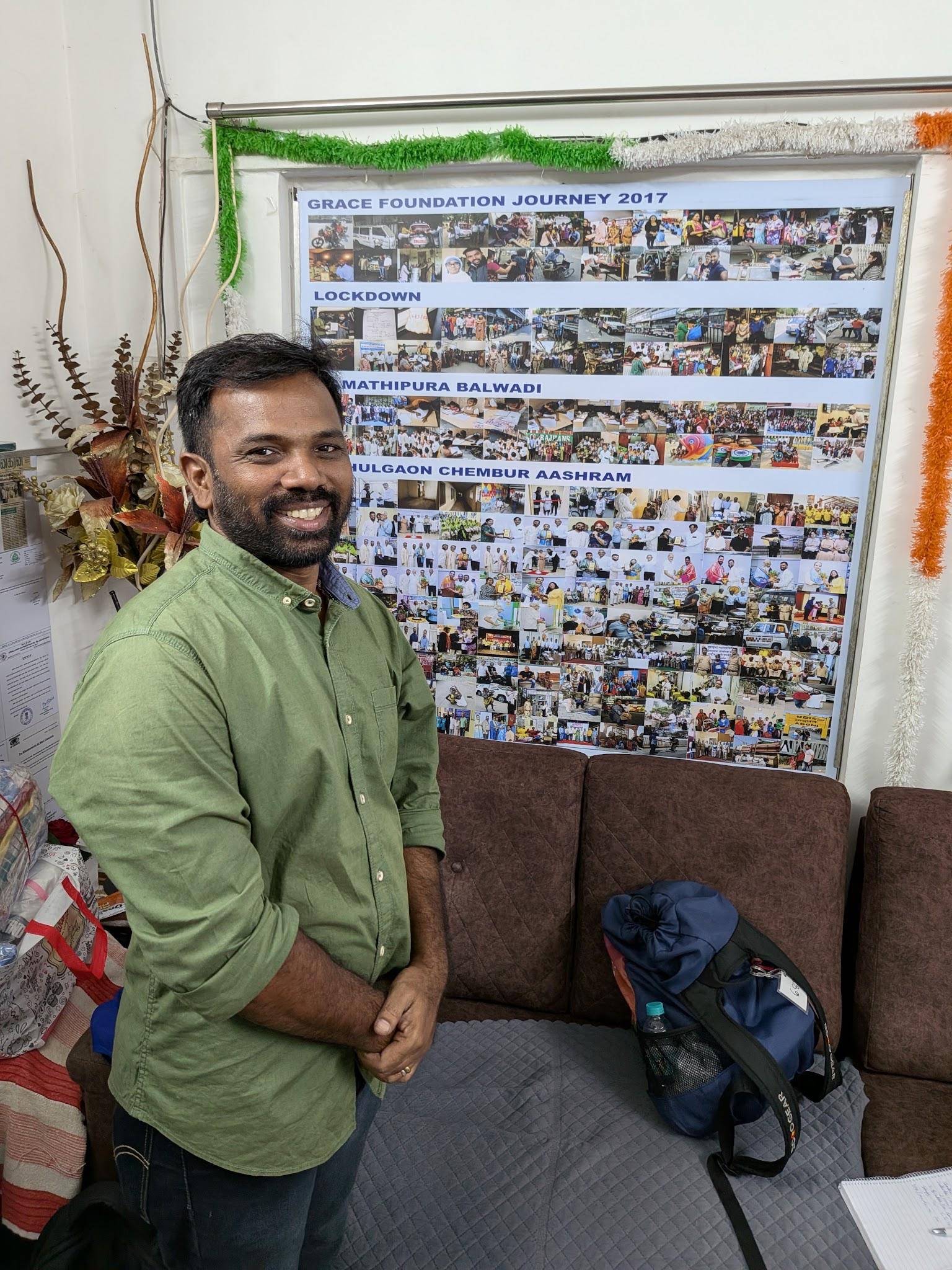 Shankar, founder of Grace Mission, in front of a wall of photographs